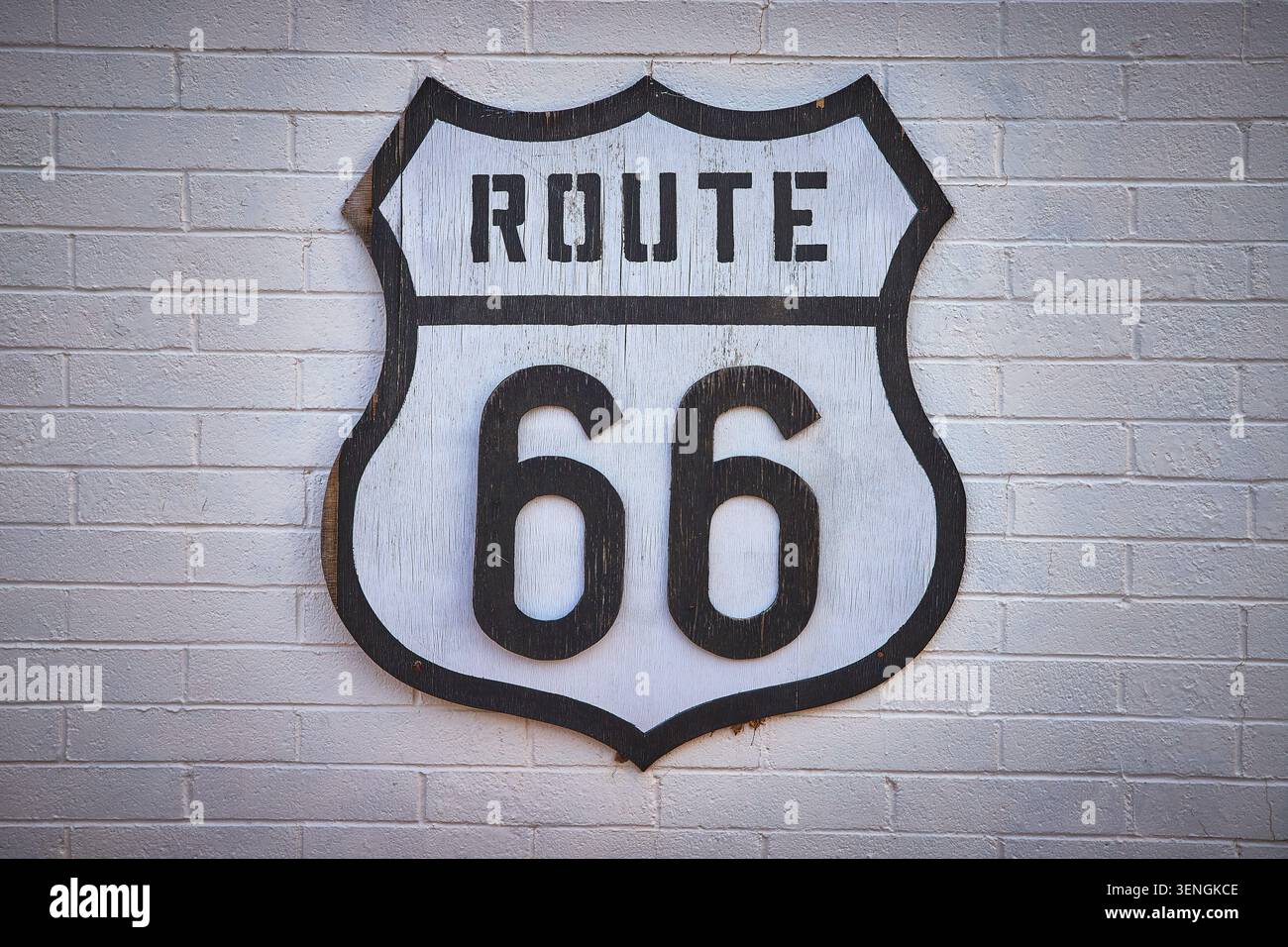 Route 66 insegna a scudo sul muro di mattoni bianchi americana Nostalgia Travel Icon Foto Stock