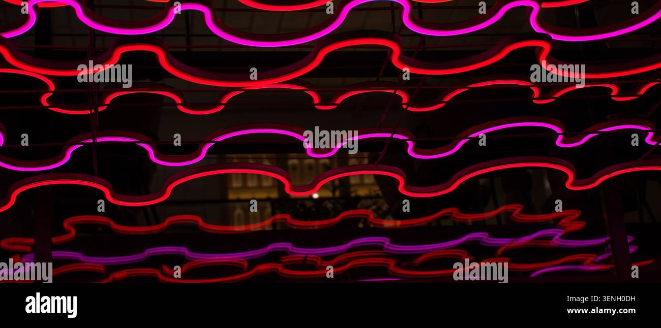 Illuminazione a LED decorativa in colori rosso cremisi con un motivo ondulato. Foto di alta qualità Foto Stock