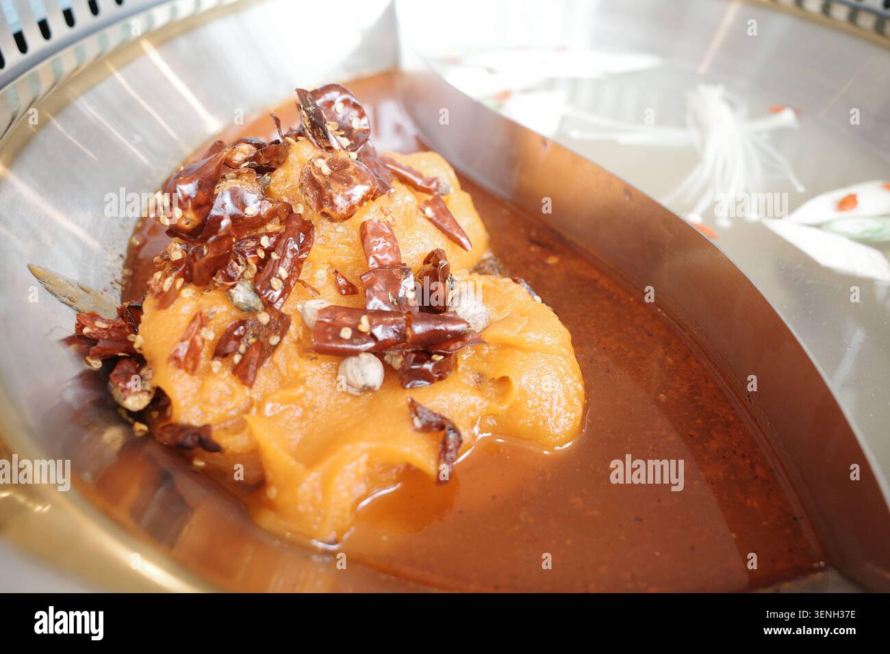 Uno shot ravvicinato cattura una ricca e vibrante base di zuppa calda di Szechuan Foto Stock