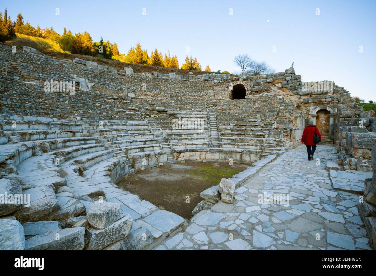 Una donna cammina attraverso l'antico anfiteatro in pietra a Selge, Turchia. Il teatro è realizzato in pietra grigia e dispone di un'area salotto semicircolare. L'atmosfera Foto Stock