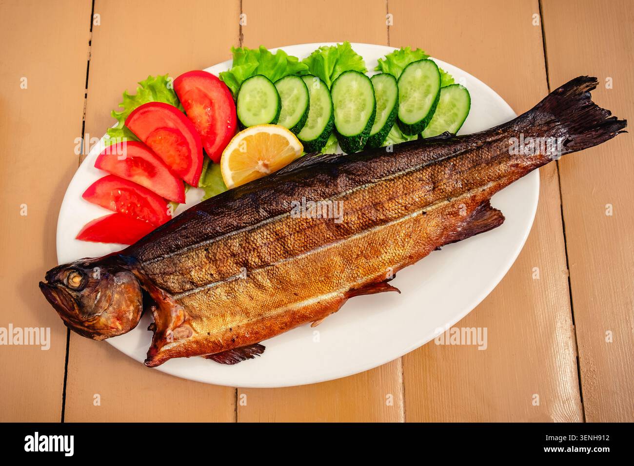Trota alla griglia con verdure su un tavolo di legno. Foto Stock