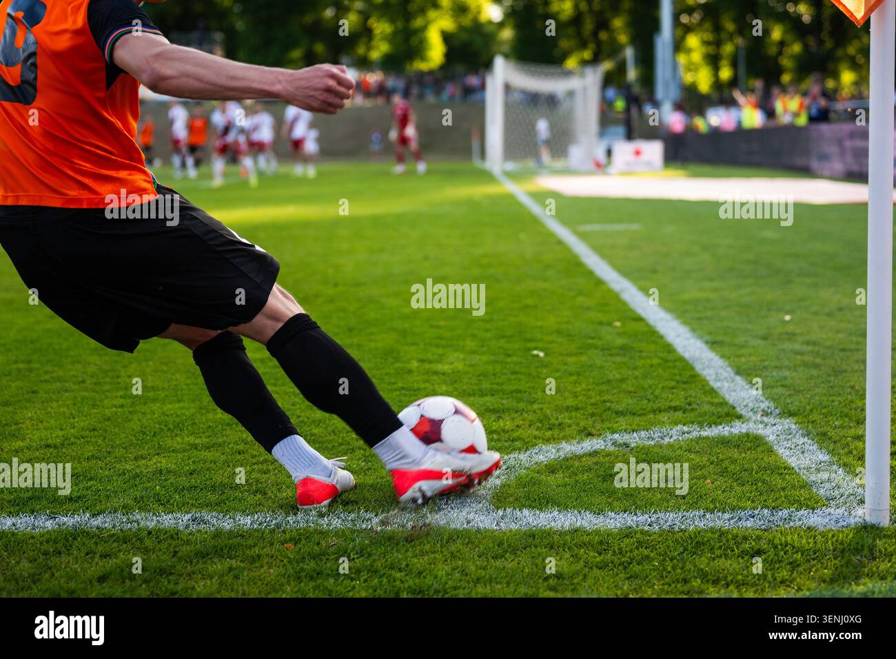 Un giocatore di calcio che calcia una palla dalla linea d'angolo durante una partita di calcio professionistico in una giornata di sole. Foto Stock