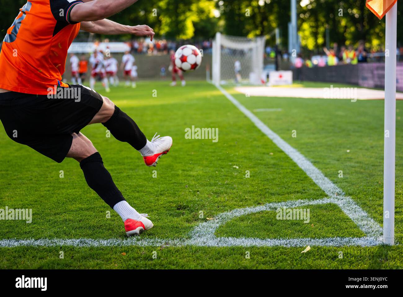 Un giocatore di calcio che calcia una palla dalla linea d'angolo durante una partita di calcio professionistico in una giornata di sole. Foto Stock