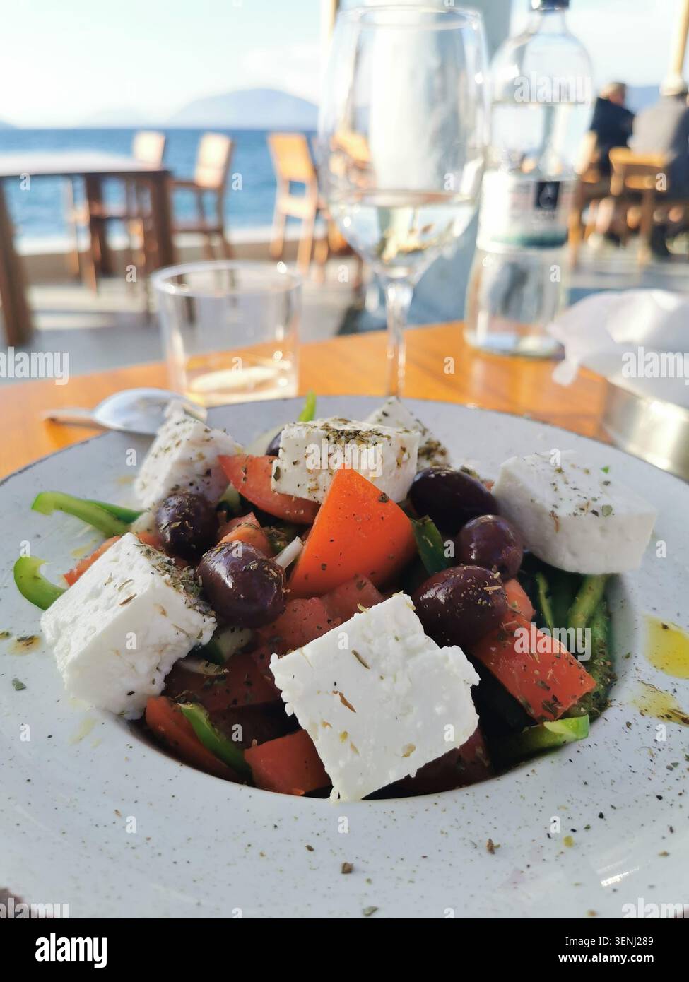 Cibo autentico con insalata greca fresca e vino al crepuscolo in una taverna sul porto. Foto di scorta della cucina greca di alta qualità per blog culinari. - Immagine stock catturata con smartphone