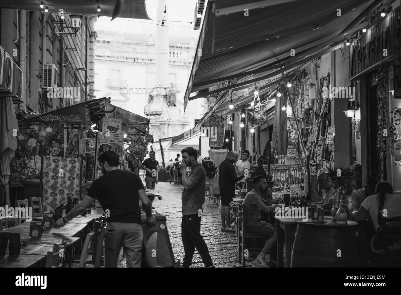 Palermo, Sicilia, Italia, 20 giugno 2025 Vista in bianco e nero di una vivace strada vecchia con caffè all'aperto e gente del centro storico. Alta qualità p Foto Stock