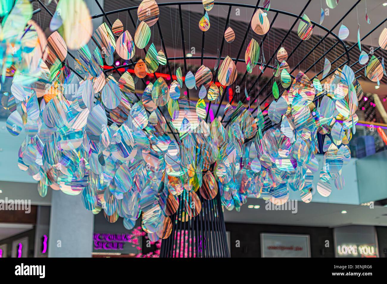 Intricata installazione decorativa sospesa con elementi a forma di goccia con superfici riflettenti e iridescenti in sfumature di blu, verde e viola Foto Stock