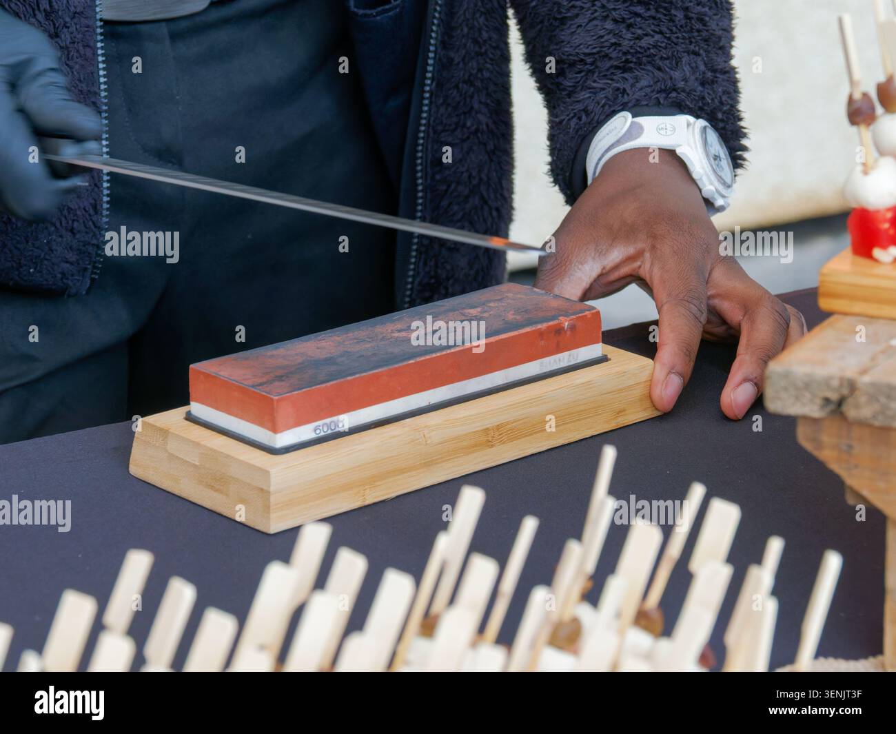 Primo piano di un prosciutto stagionato professionale tagliato a fette da una gamba di prosciutto con un coltello, tipico della salumeria europea, in Francia. Foto Stock