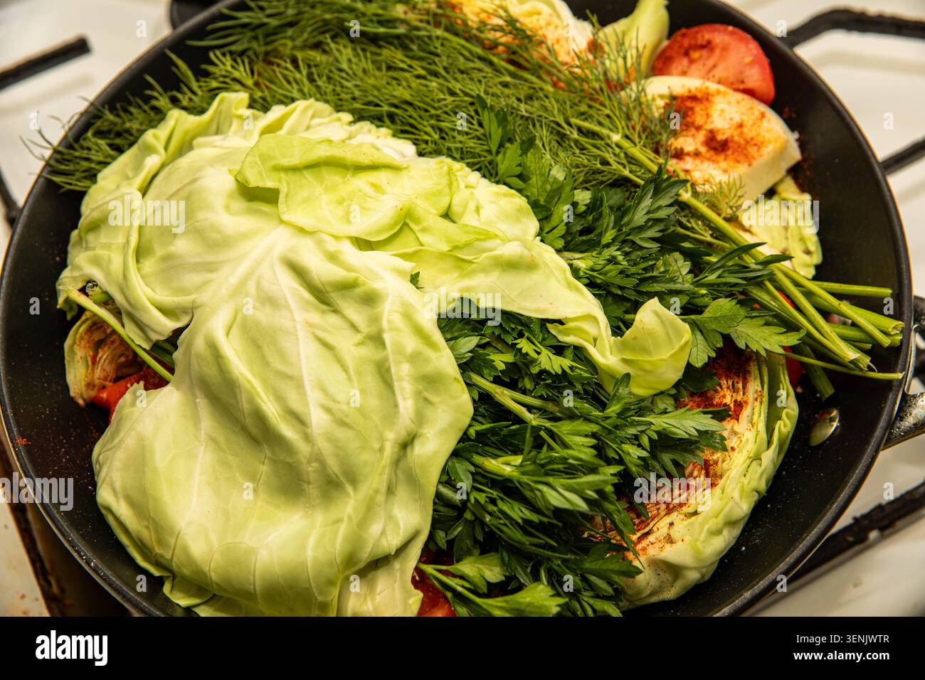 basma uzbeko tradizionale ricoperto di foglie di cavolo, aneto e prezzemolo in un kazan, pronto per la cottura lenta e la cottura al vapore alla perfezione. Foto Stock