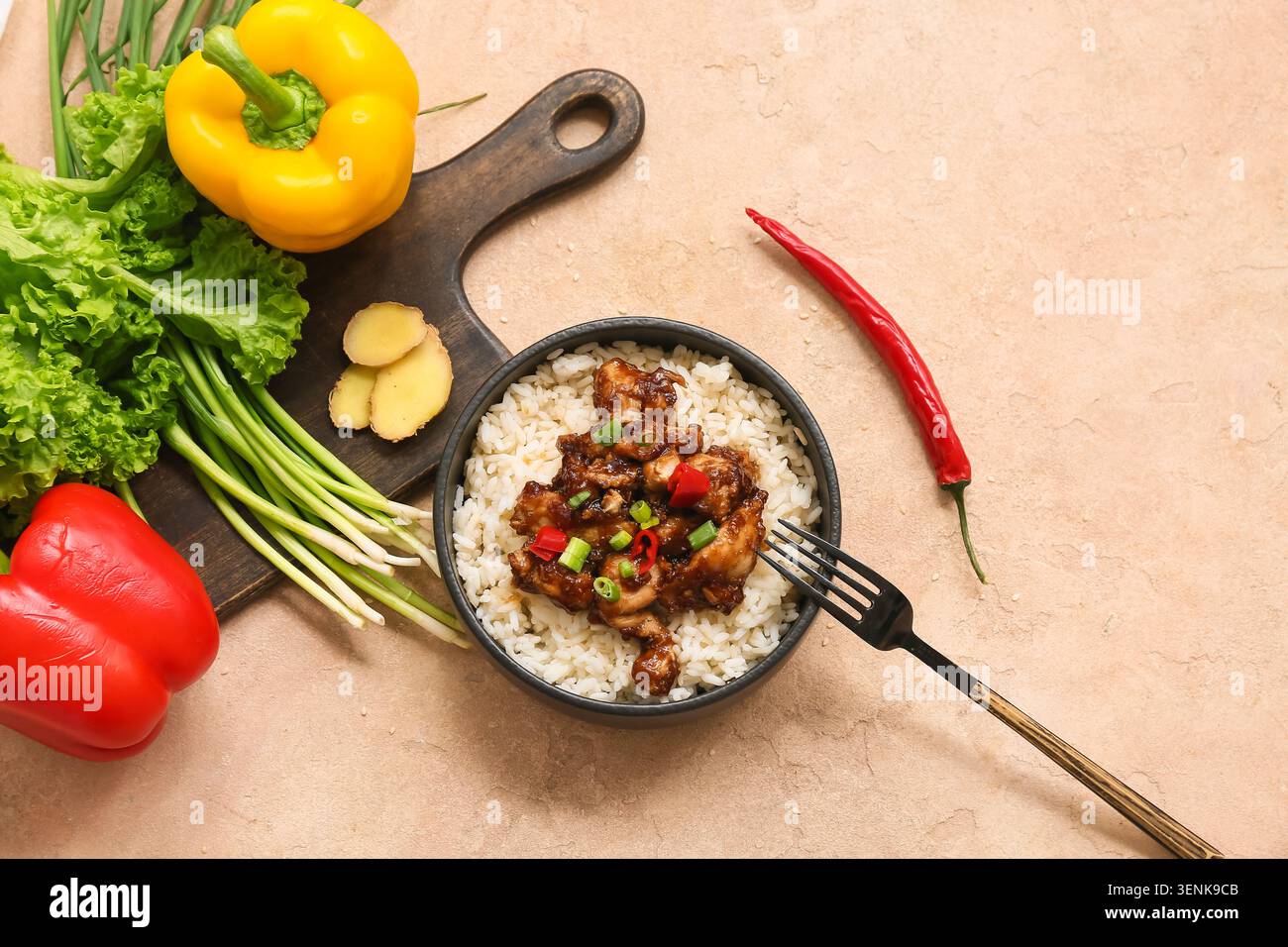 Gustoso pollo agrodolce con riso nel recipiente, verdure e forchetta su fondo grunge beige Foto Stock