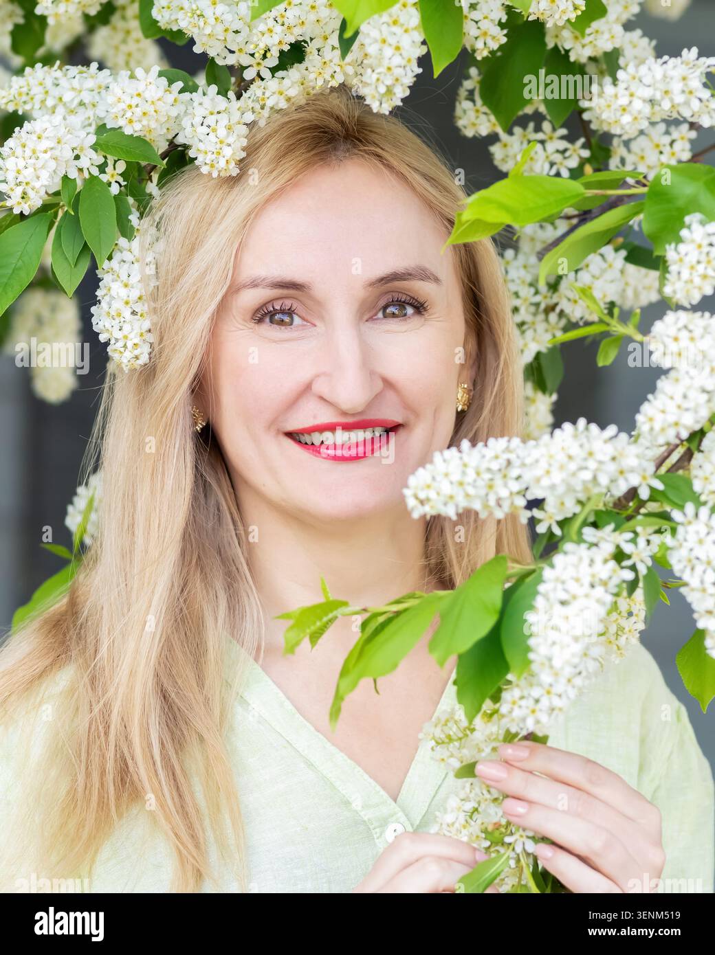 Persone vere, semplice e autentica bellezza naturale di una donna bionda caucasica con un sorriso sincero che indossa una camicia di cotone leggero. Scena in un parco primaverile al b Foto Stock