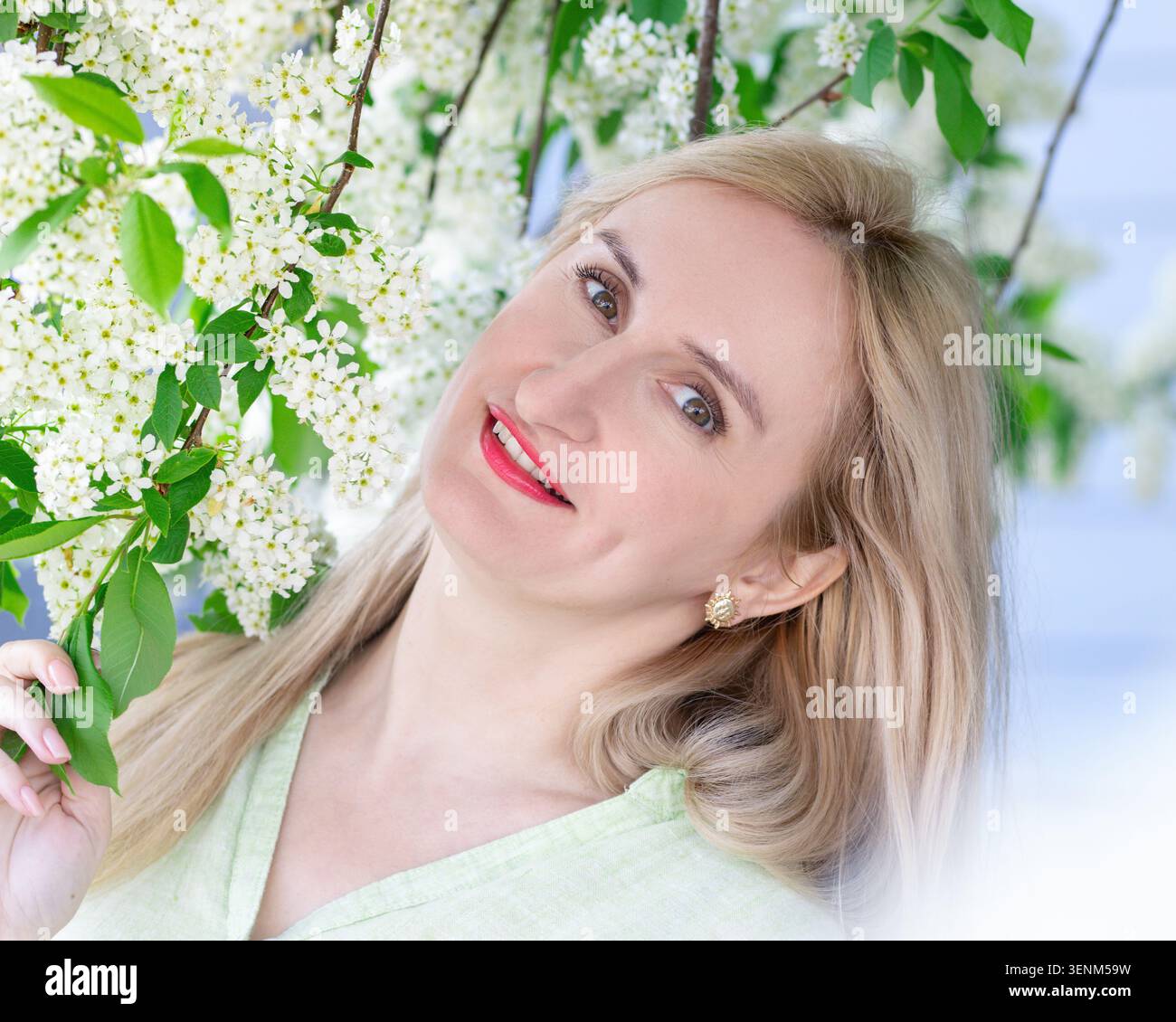 Persone vere, semplice e autentica bellezza naturale di una donna bionda caucasica con un sorriso sincero che indossa una camicia di cotone leggero. Scena in un parco primaverile al b Foto Stock