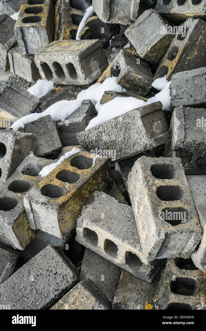 Una vista ravvicinata ad angolo alto cattura una grande pila di blocchi di cemento scartati, alcuni dei quali presentano uno scolorimento giallo-arancione e dei fori. Patch di Foto Stock