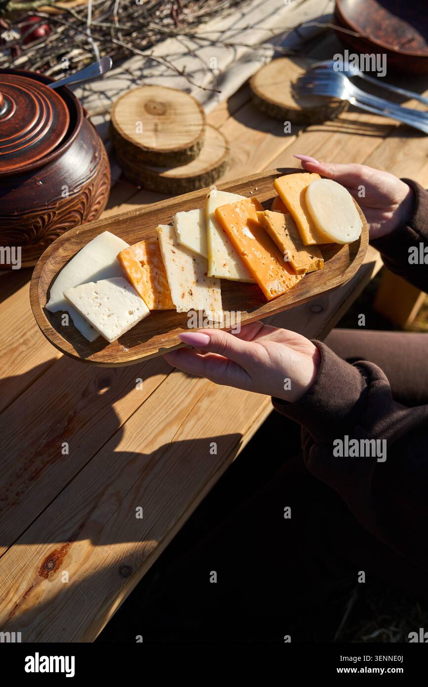 Degustazione di formaggi su una tavola di legno sotto il cielo aperto. Foto Stock