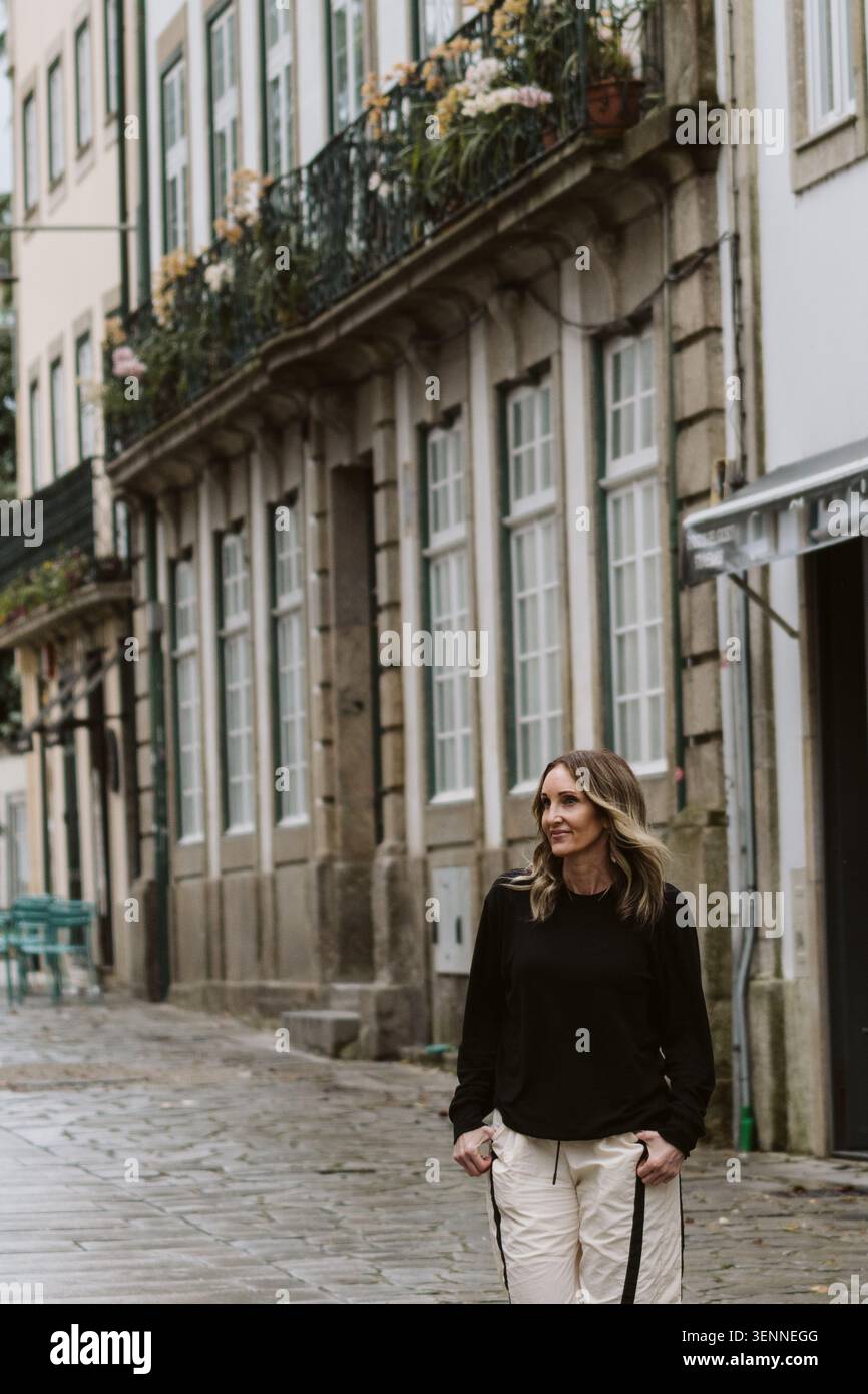 Donna elegante che cammina su una vecchia strada acciottolata Foto Stock