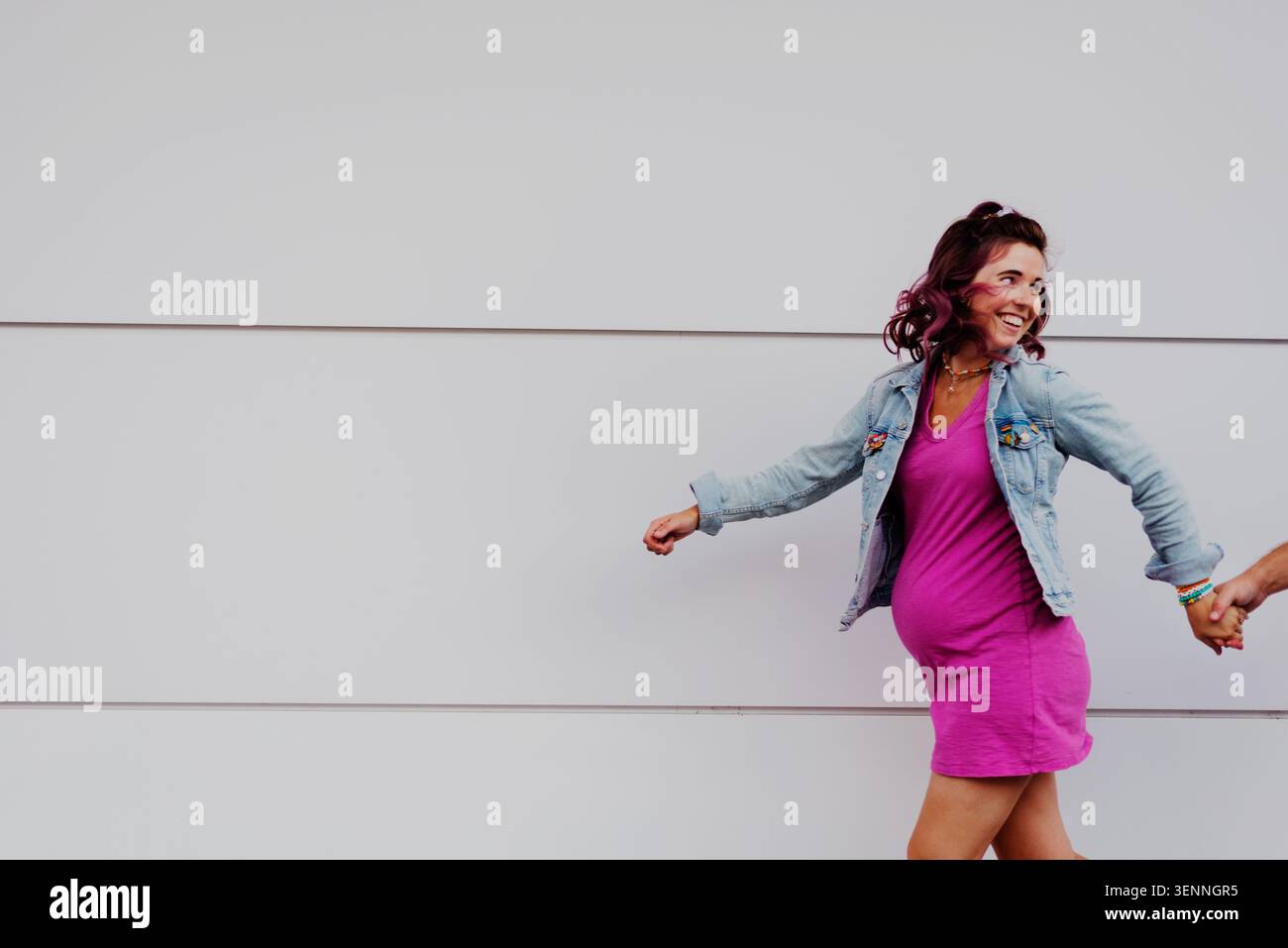 Donna incinta gioiosa che si tiene per mano e cammina Foto Stock