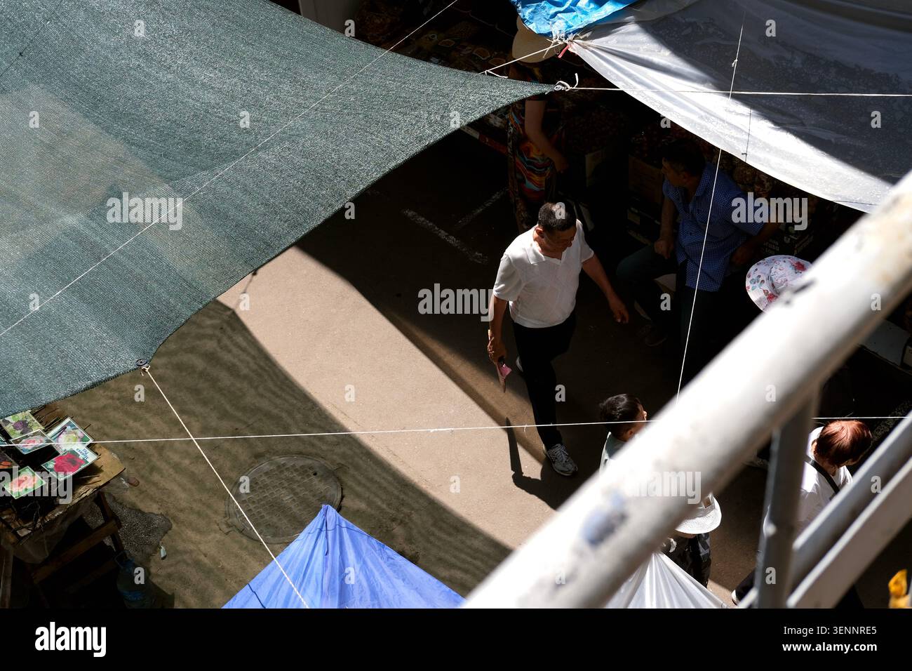 Almaty, Kazakistan - giugno 2026: Una vista dall'alto di un uomo che cammina sotto le tettoie ombreggiate al mercato all'aperto del Bazar Verde. Foto Stock