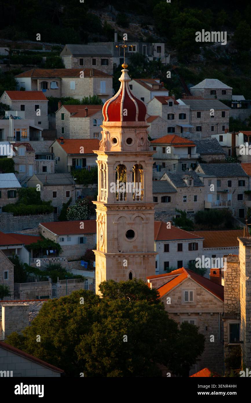 La chiesa di Pucisca sull'isola croata del Mediterraneo di Brac, inondata dalla luce del sole che tramonta. Un idillio estivo in questa piccola località di villeggiatura, Foto Stock