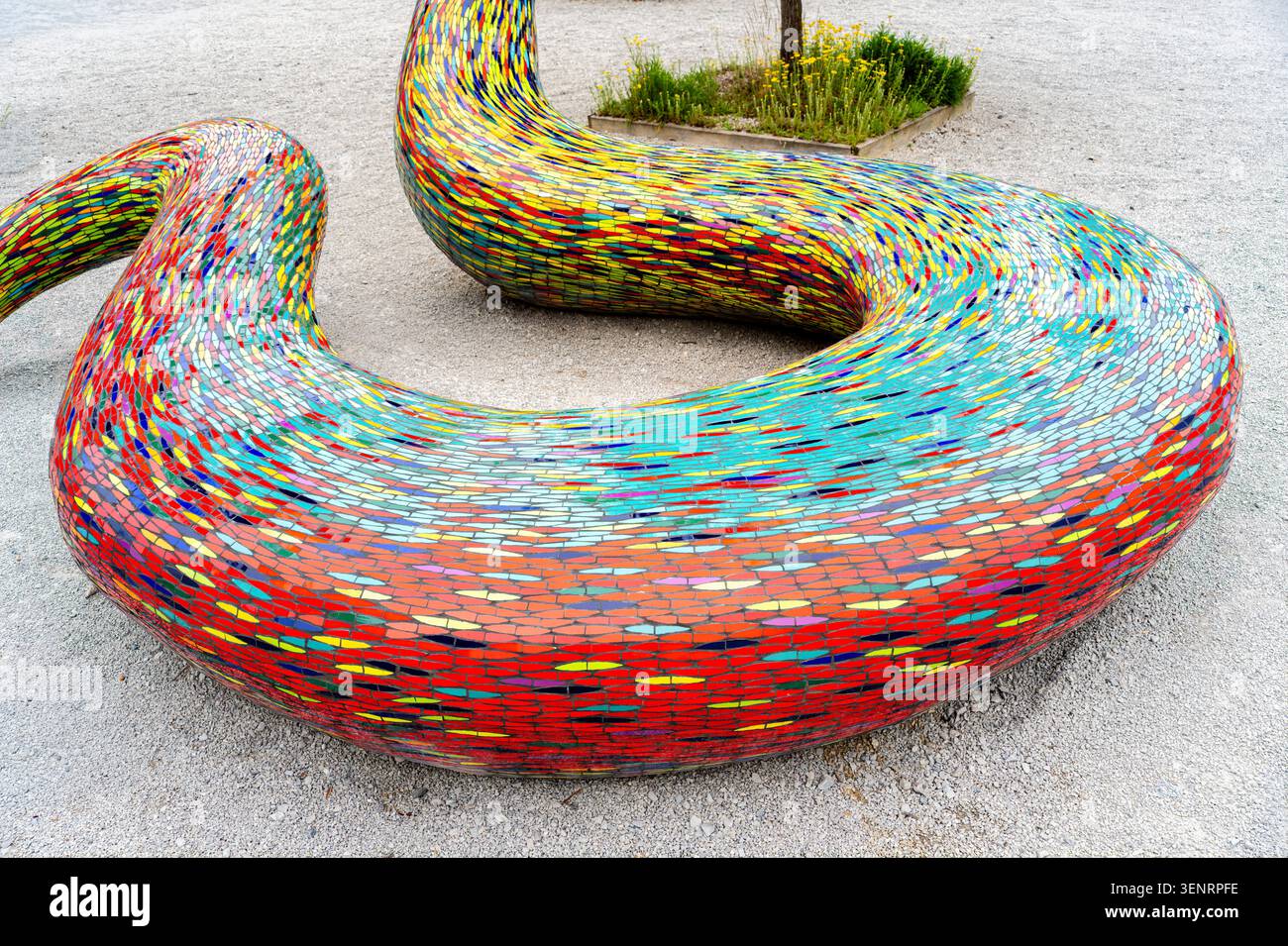 Losanna, Svizzera - 4 giugno 2026: Panca a mosaico ricurvo colorato a forma di serpente, con vivaci motivi delle piastrelle e una forma astratta giocosa su un g Foto Stock