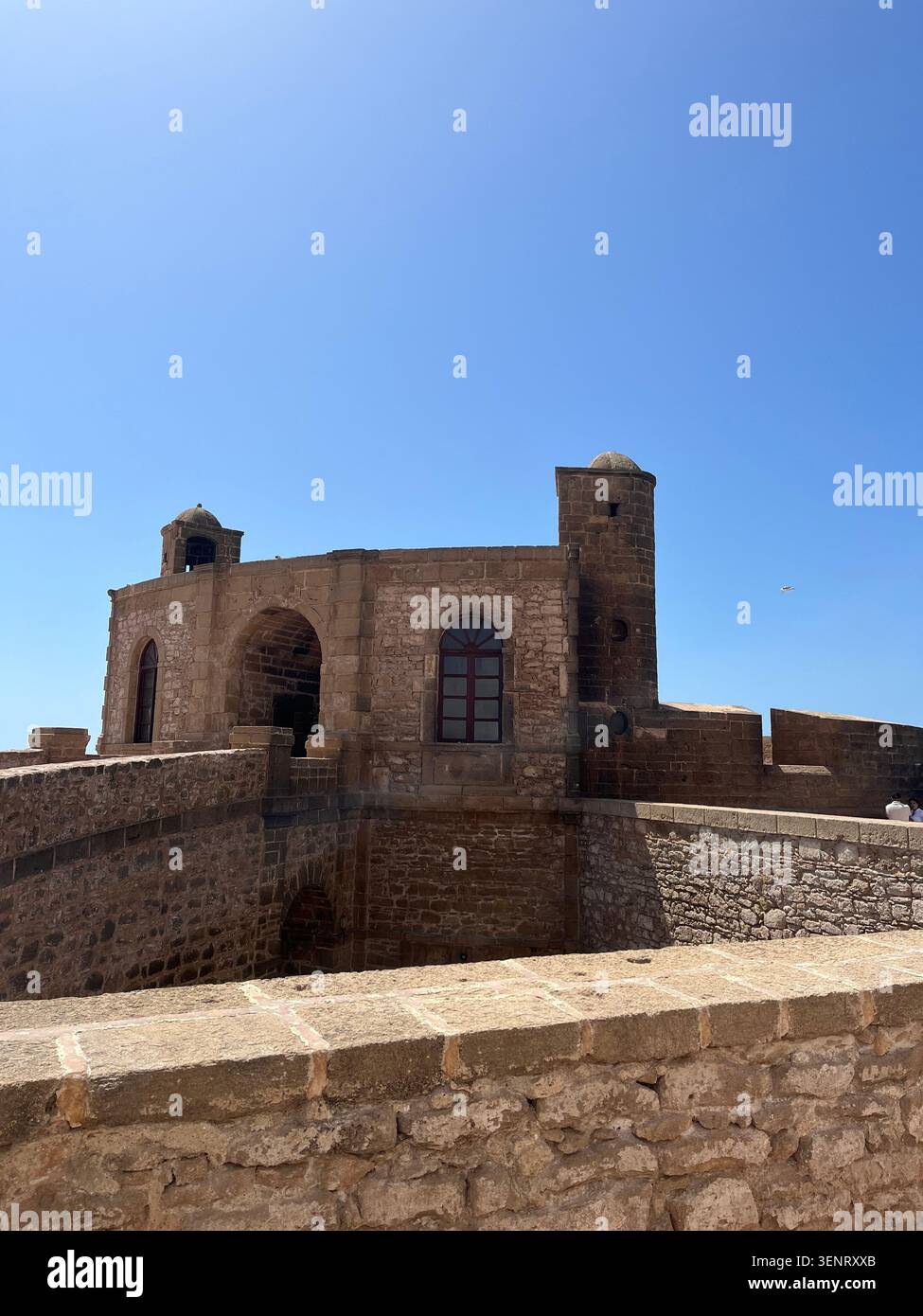 Storica fortezza in pietra e mura difensive a Essaouira, Marocco, sotto un cielo azzurro. - Immagine stock catturata con smartphone