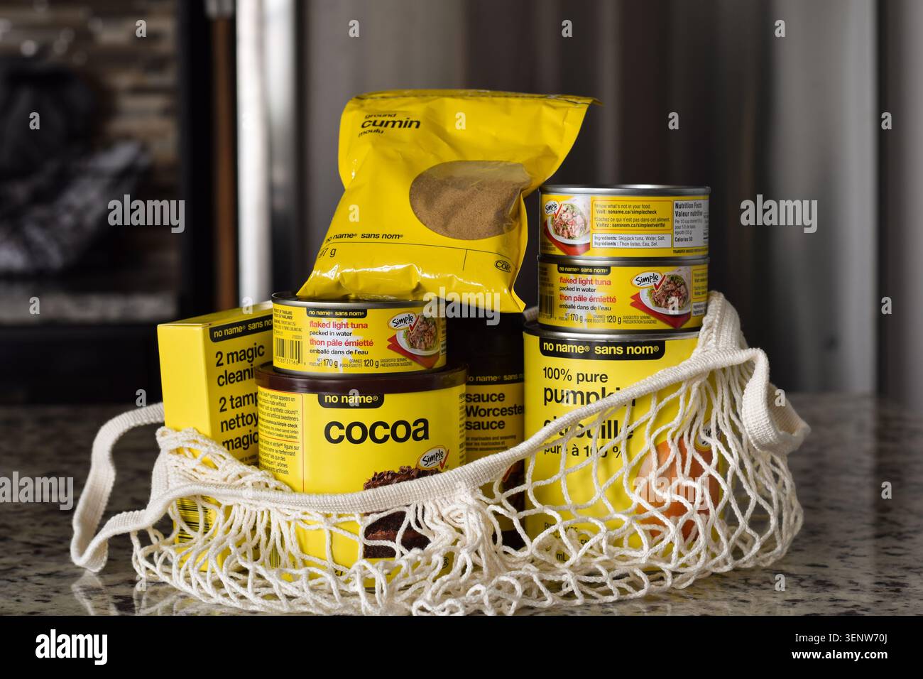Prodotti alimentari assortiti senza nome economici all'interno di una borsa in rete in macrame riutilizzabile posizionata su un bancone della cucina in un ambiente domestico Foto Stock