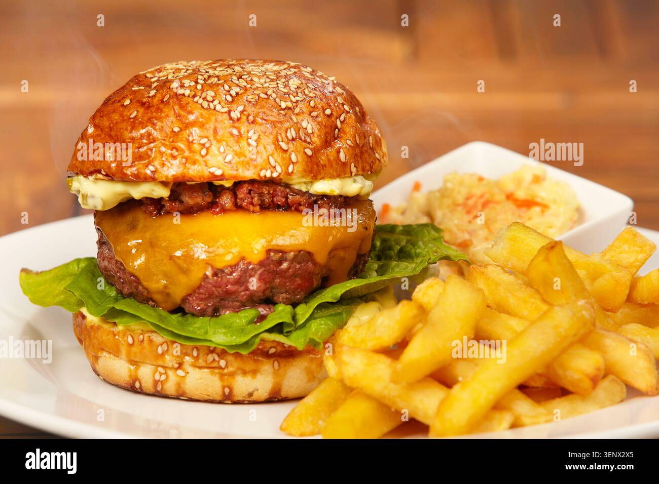 Hamburger di manzo di lusso in panino con formaggio, marmellata di pancetta, lattuga, patatine fritte e insalata di cavolo Foto Stock