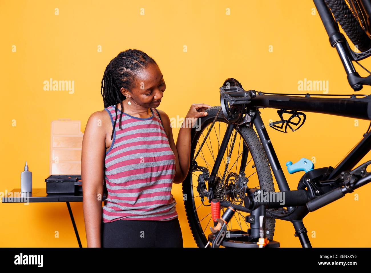 Donna dedicata che controlla gli pneumatici per biciclette per rilevare eventuali danni da riparare con attrezzature professionali. Foto Stock