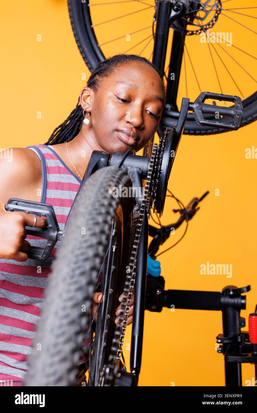 Donna che analizza da vicino la catena di biciclette con donna dedicata che analizza attentamente la catena di biciclette per mantenere l'efficienza del ciclo. Foto Stock