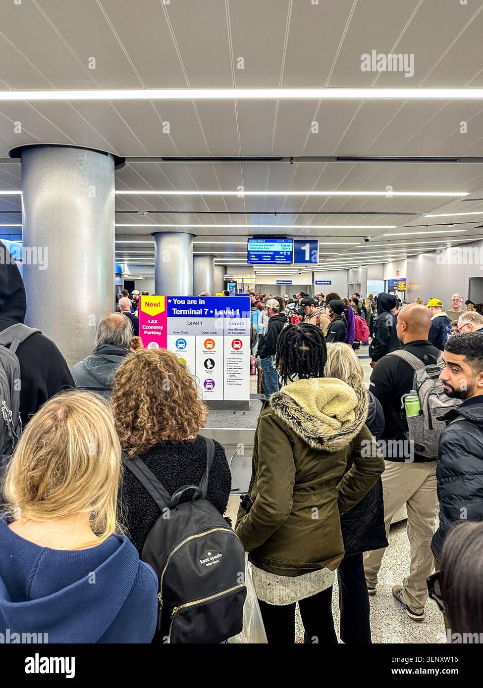 I passeggeri frustrati aspettano i loro bagagli al ritiro bagagli al Terminal 7 dopo un lungo volo di andata e ritorno Foto Stock