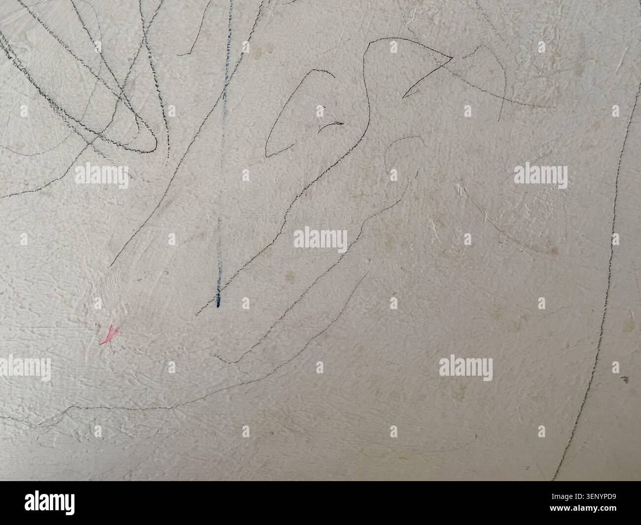 Primo piano di una parete con texture beige chiaro ricoperta da scarabocchi casuali realizzati con matite. Foto Stock