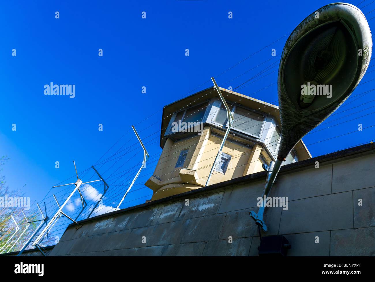 Vista dall'angolo basso della torre di guardia, del muro di sicurezza e della recinzione perimetrale presso il Memoriale di Berlino-Hohenschönhausen, la forma. Prigione della Stasi. Foto Stock