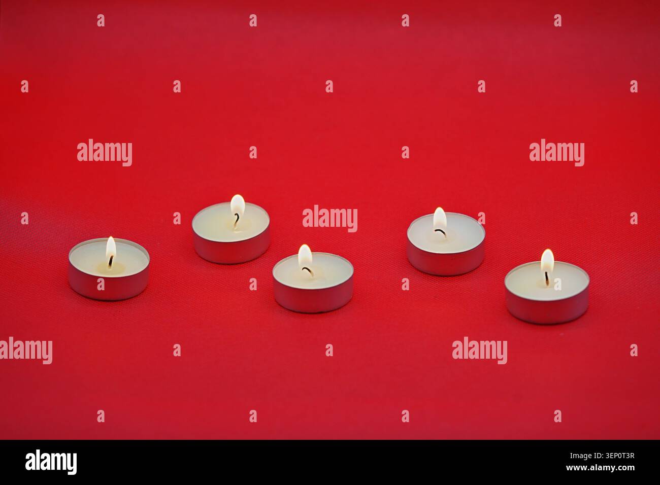 Cinque piccole candele rotonde bruciate su sfondo rosso brillante. Foto di alta qualità Foto Stock