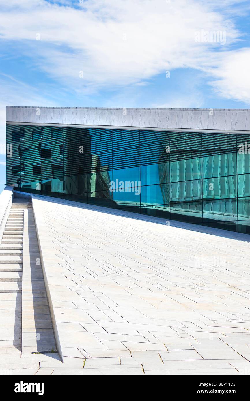 Architettura moderna del Teatro dell'Opera di Oslo con il suo tetto in marmo bianco e la facciata in vetro sotto un cielo blu in Norvegia Foto Stock