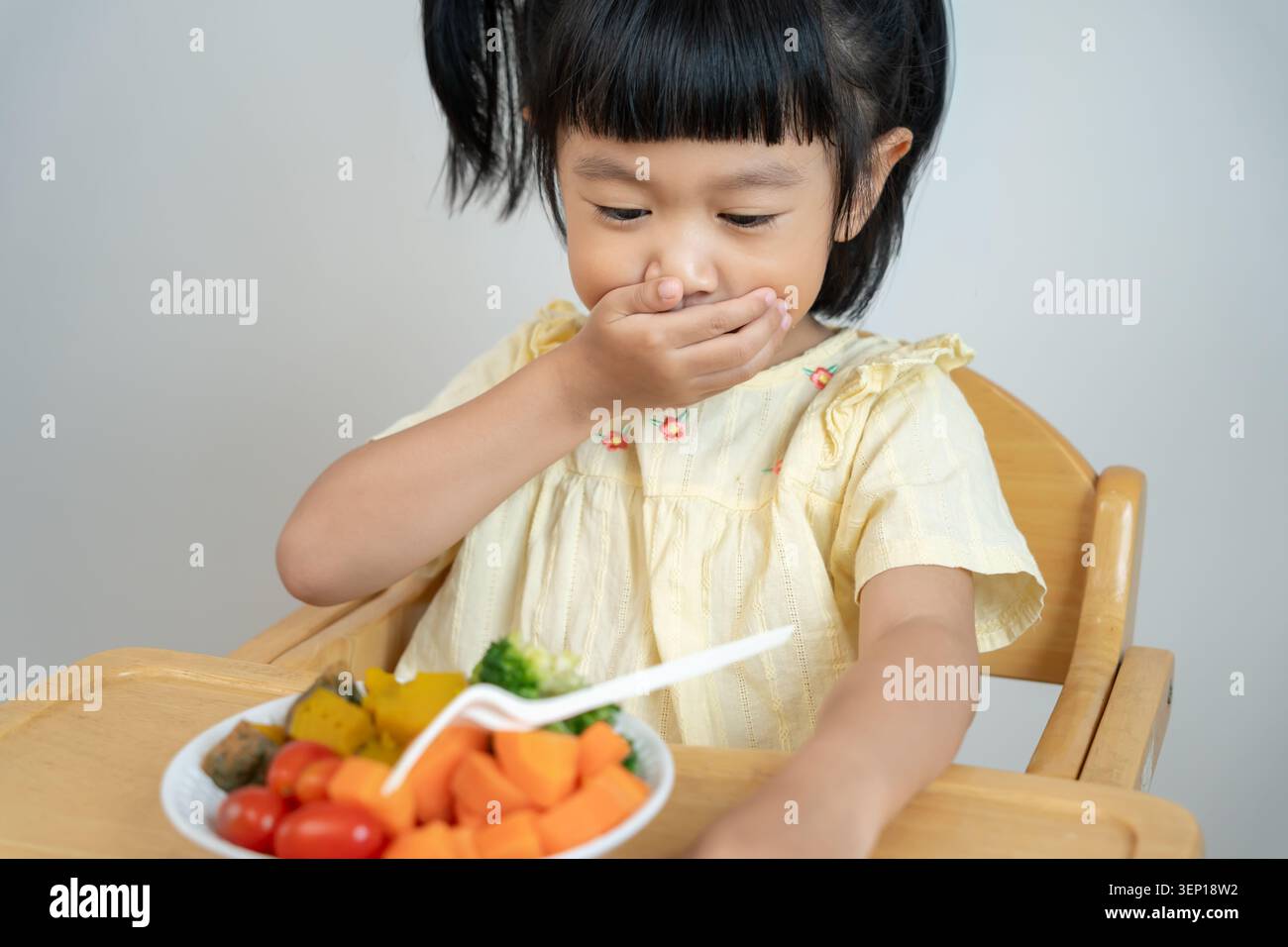 I bambini coprono la bocca senza mangiare verdure, sapore amaro, odore particolare, aspetto poco attraente, bruciare le verdure fuori dal piatto, rifiuto, nutrizione Foto Stock