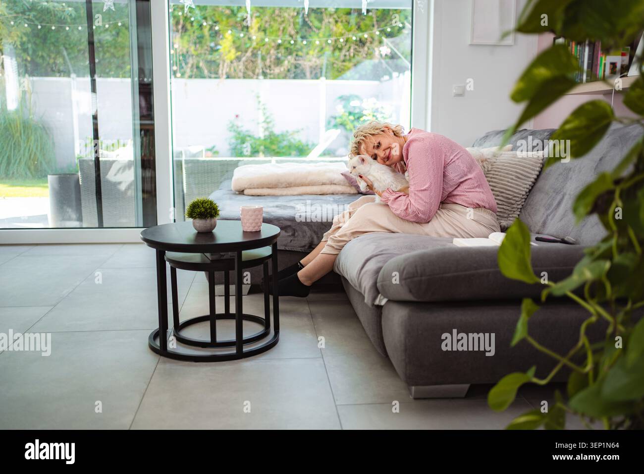 Donna adulta che si rilassa sul divano coccolando il cane Foto Stock