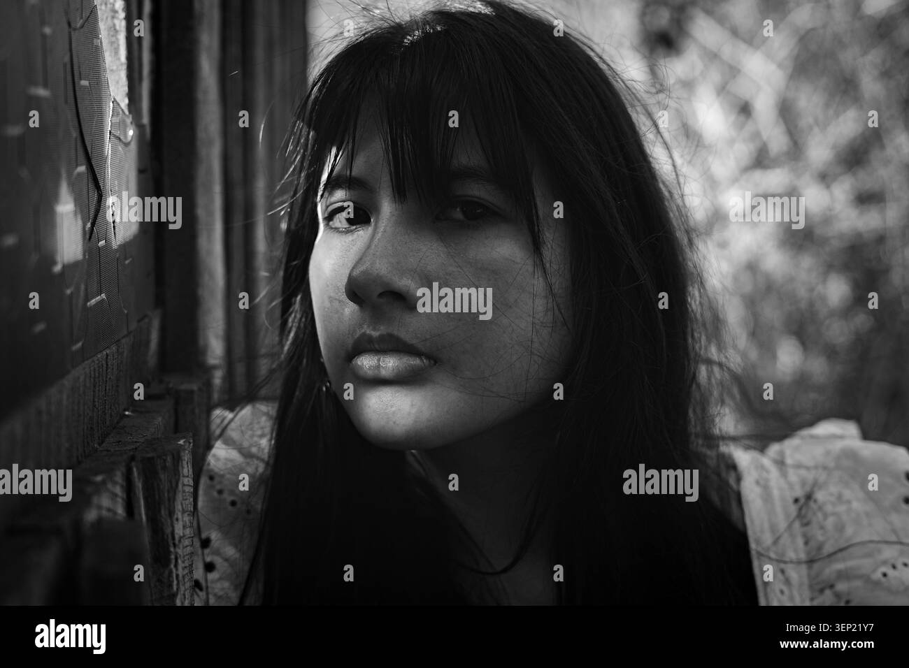 Ritratto di una giovane donna in bianco e nero all'aperto, espressione premurosa e premurosa su un morbido sfondo naturale che trasmette introspezione, silenziosa Foto Stock