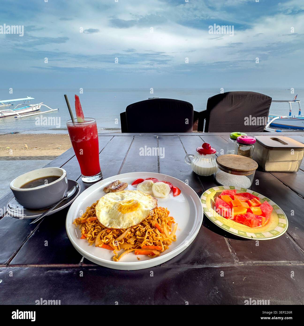 Colazione in spiaggia con mi Goreng (spaghetti amici), frutta fresca, succo di anguria fresca e caffè a Bali Foto Stock