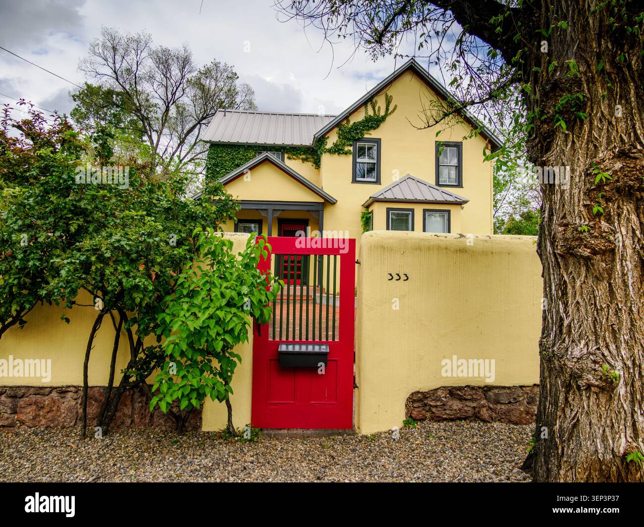 Santa Fe, NM - 6 maggio 2026 - pareti gialle e un cancello rosso brillante creano una colorata scena stradale al 333 di Canyon Road Foto Stock