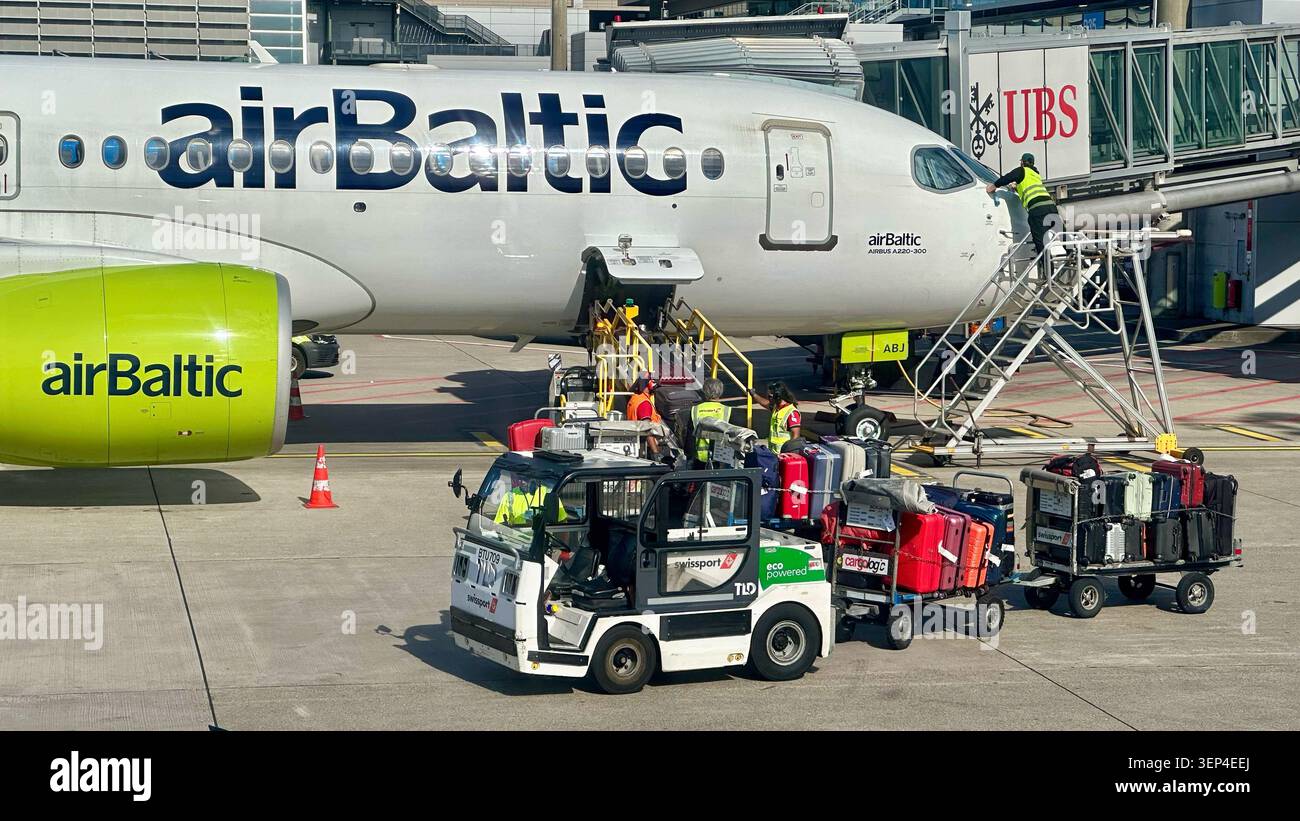 L'equipaggio di terra di Swissport serve un Airbus A220-300 AirBaltic durante il turnaround all'aeroporto di Zurigo. Foto Stock