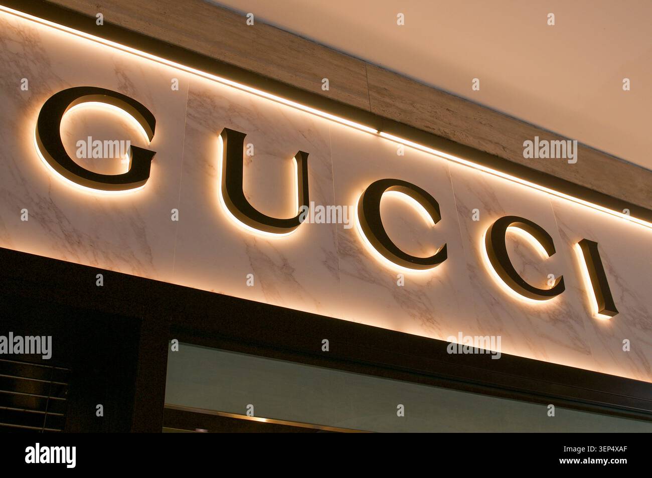 Lugano, Ticino, Svizzera - 24 maggio 2026: Elegante primo piano orizzontale dell'insegna retroilluminata del negozio di moda Gucci su un faca in marmo bianco Foto Stock