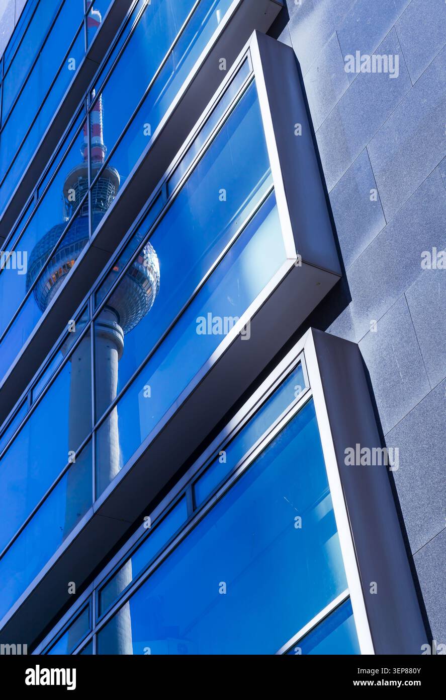 Riflesso dell'iconica torre della televisione di Berlino (Fernsehturm) nella facciata di vetro di un moderno edificio per uffici. Architettura astratta con linee geometriche. Foto Stock