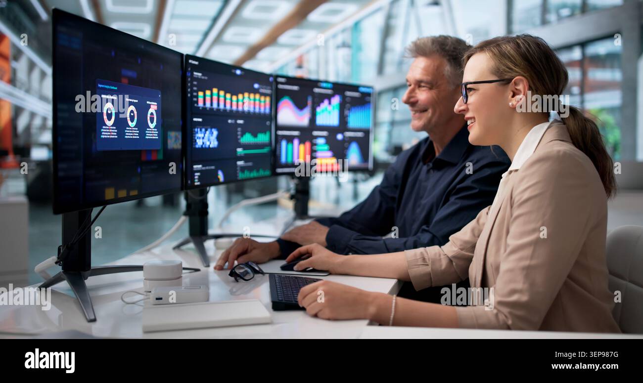 Due analisti finanziari condividono Un momento di gioia durante la revisione dei dati insieme. Foto Stock