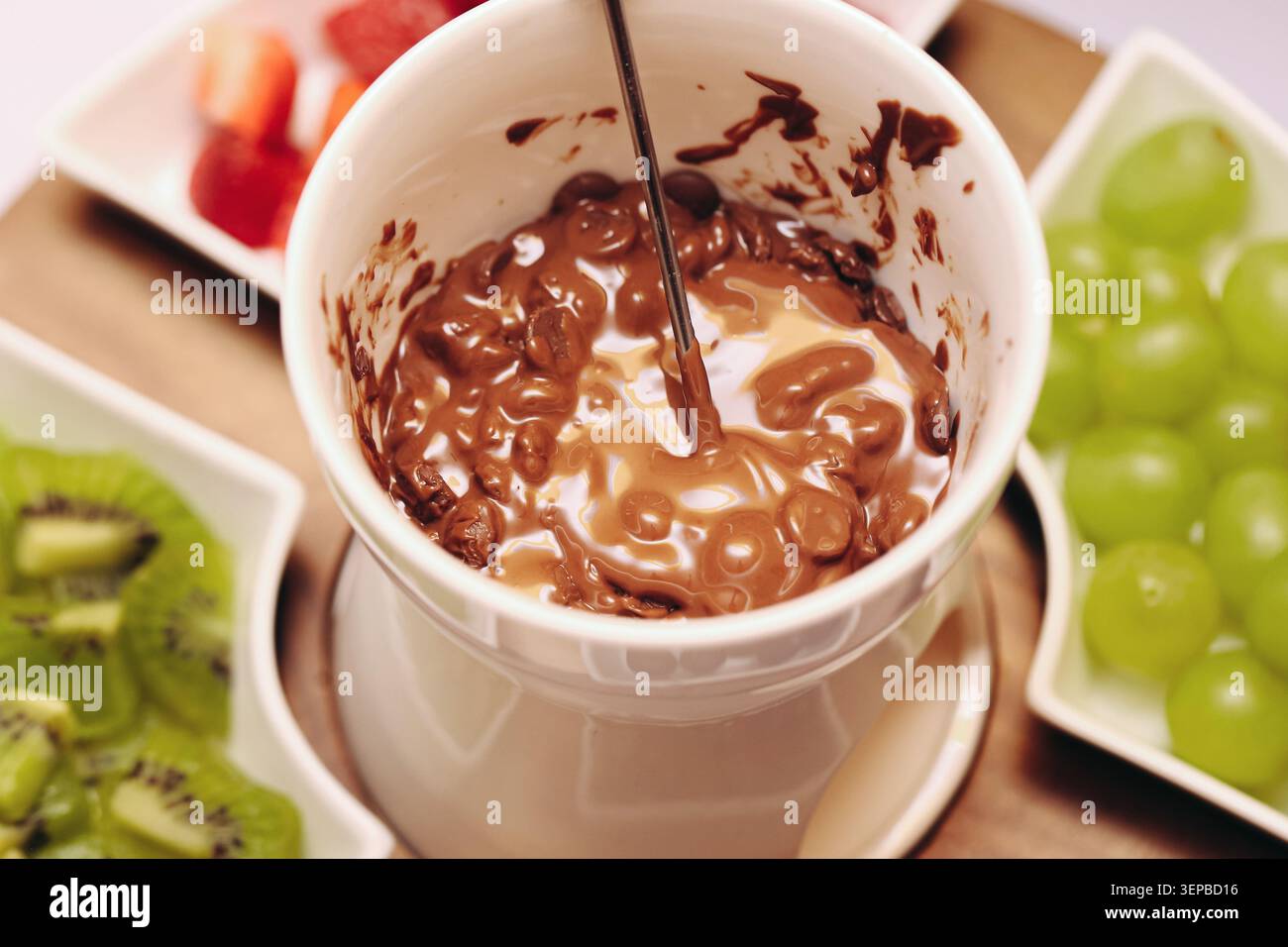 Fonduta al cioccolato fusa in tazza di ceramica con frutta fresca. Dessert dolce per spuntini e feste e prelibatezze fatte in casa. Foto Stock