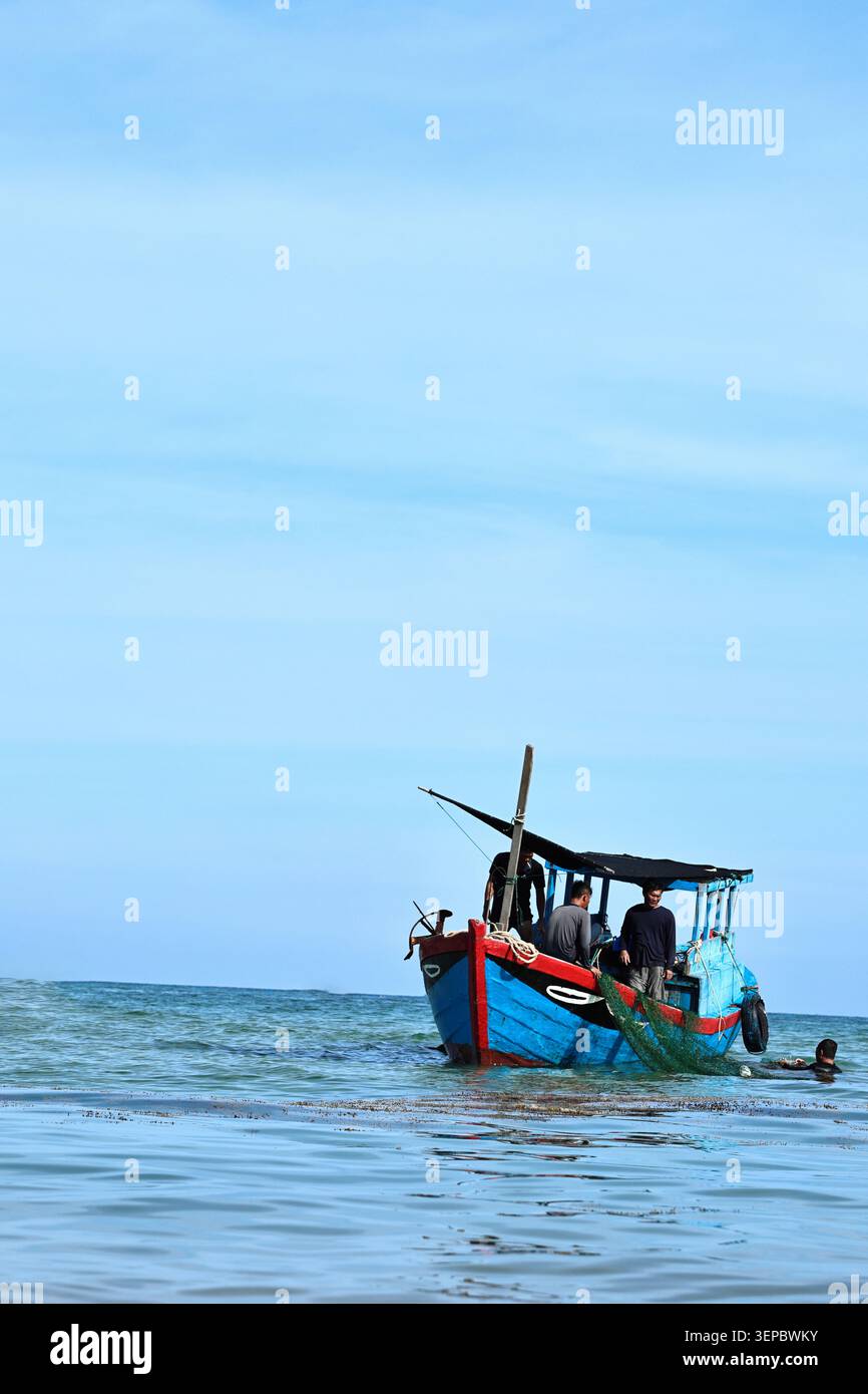 Pescatori che lavorano su un peschereccio in legno in mare aperto Foto Stock
