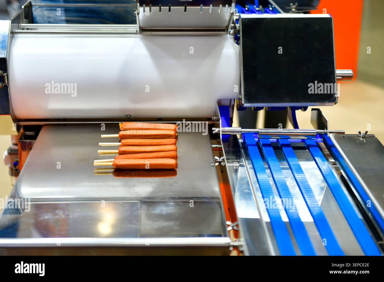 Moderni macchinari industriali per la produzione di alimenti che producono salsicce fresche con bastoncini di legno in fabbrica Foto Stock