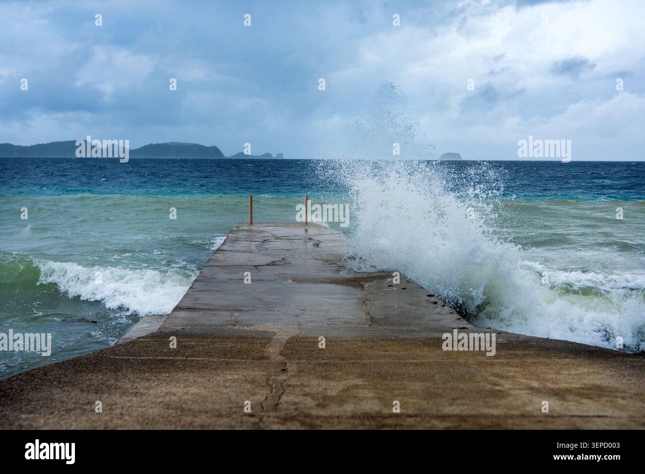 Una spettacolare ripresa a livello degli occhi di una grande onda oceanica che si schianta violentemente contro un molo di cemento intemprato. Foto Stock