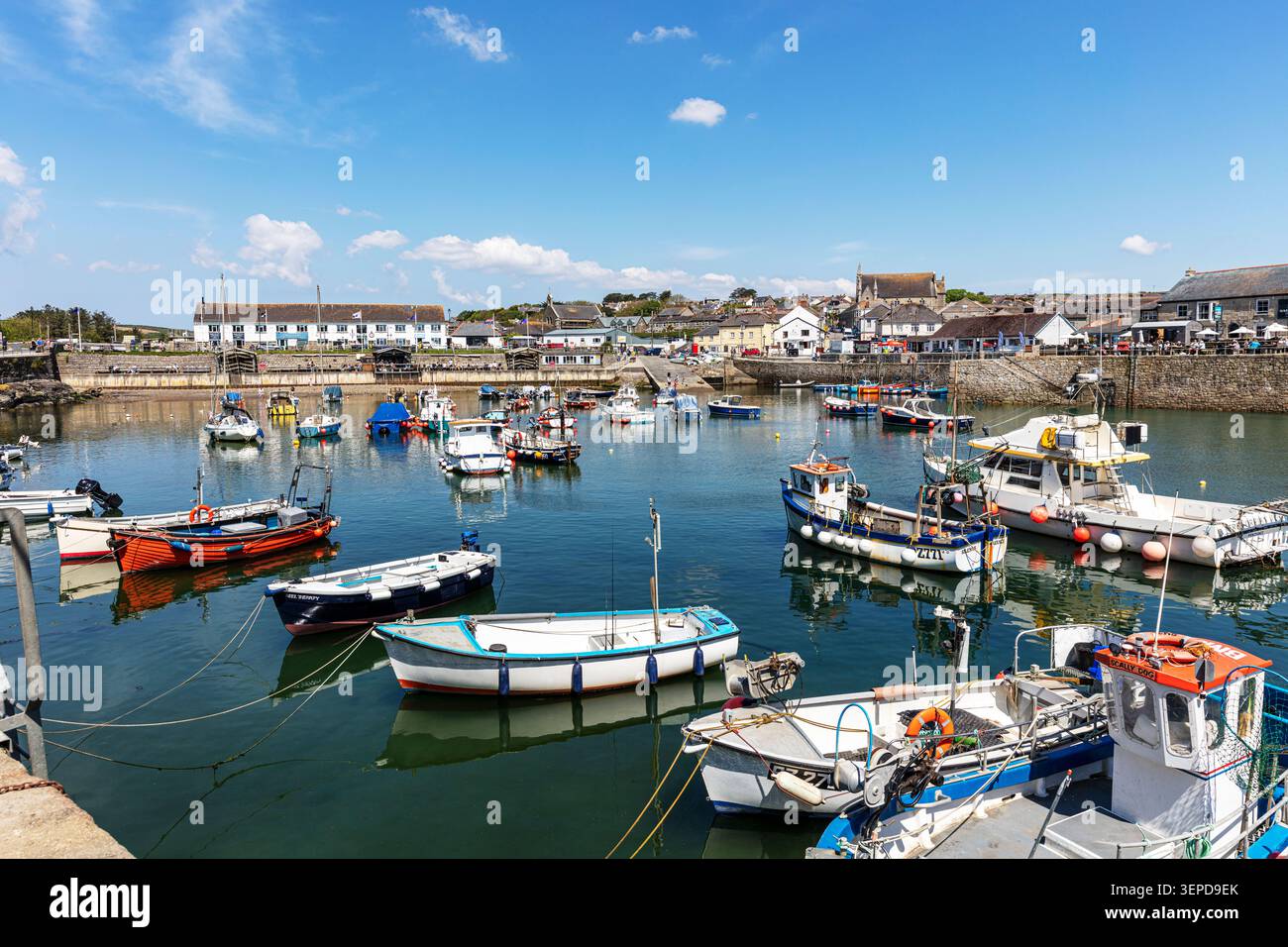 Scena del porto a Porthleven in Cornovaglia, che mostra piccole barche da pesca e imbarcazioni da diporto ormeggiate in acque calme. Edifici bianchi e in pietra fiancheggiano il Foto Stock