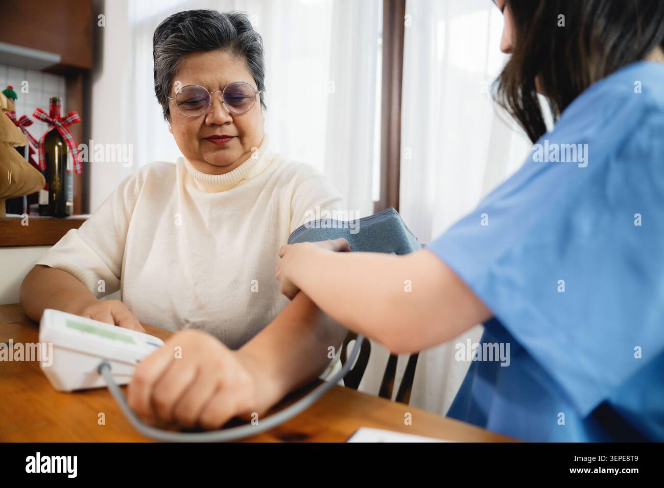 Donna asiatica anziana che riceve il controllo della pressione sanguigna medico mentre la giovane infermiera utilizza lo sfigmomanometro digitale senior, geriatrico servizio di assistenza infermieristica routi Foto Stock