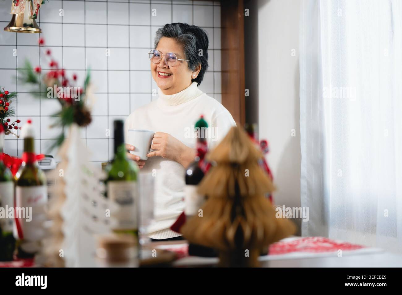 Felice anziana nonna in pensione bevendo tè stagione natalizia, occhiali sorridenti vacanza invernale festa in casa, stile di vita sano invecchiamento nonna asiatica Foto Stock