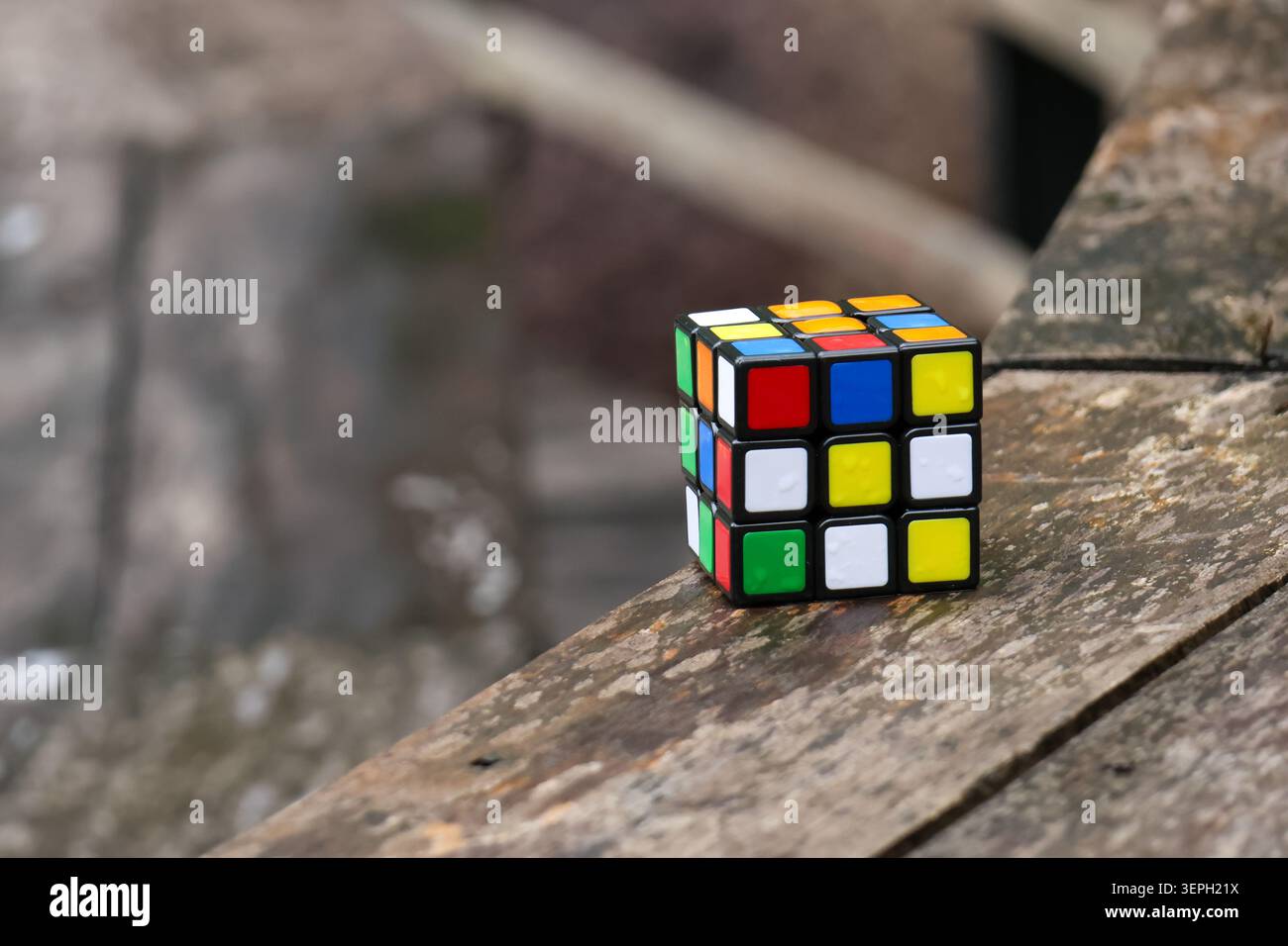 Colorato e irrisolto puzzle cubo di plastica giocattolo in plastica per esterni superficie in legno sfida fuoco gioco mentale svago attività cerebrale logica strategia divertimento Foto Stock