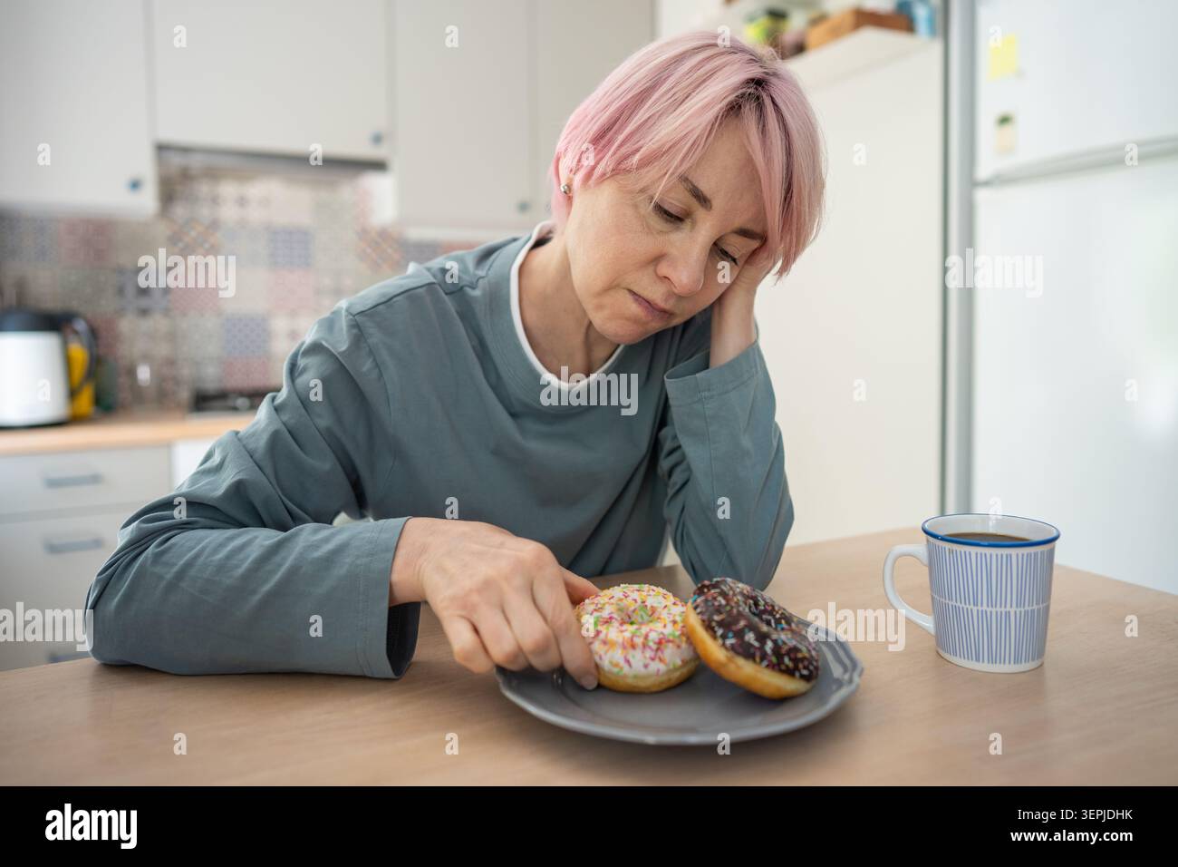 Stressata e turbata donna matura tossicodipendente si sente in colpa per il debole stato mentale mangia spuntini di cibo spazzatura. Foto Stock